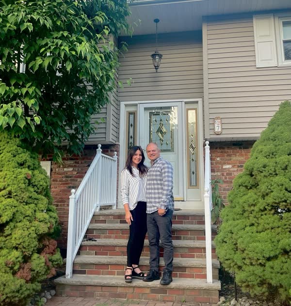 Homeowners on the front steps of their new home